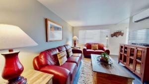 摩押Downtown Cozy Home Base - Purple Sage 5的客厅配有红色皮革沙发和桌子