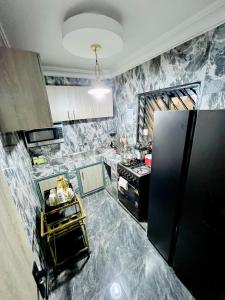雅温得The Jumeirah Guest Home的厨房设有大理石墙壁和黑色冰箱。