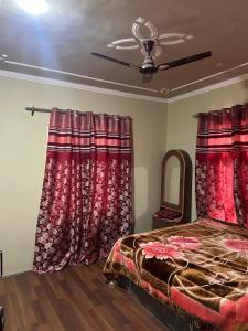 斯利那加Home sleeper的一间卧室配有红色窗帘、一张床和镜子