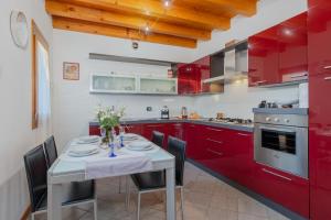 Sarcedo[Marostica - Villa with Swimming Pool] Netflix - WiFi的厨房配有红色橱柜和桌椅