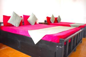 马纳尔Thalladi Holiday Bungalow的配有红色和白色枕头的客房内的两张床