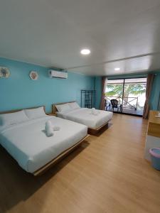刁曼岛Home Away Tioman Island的配有蓝色墙壁和木地板的客房中的两张床