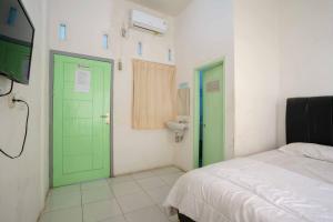 LampungLyfriska Residence Lampung RedPartner的一间设有绿门、一张床和水槽的客房