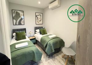 伦敦FW Haute Apartments at Enfield, Pet Friendly Ground Floor 3 Bedrooms and 2 Bathrooms Flat with King or Twin beds with Garden and FREE WIFI and FREE PARKING的小客房内的两张床,配有绿色床单