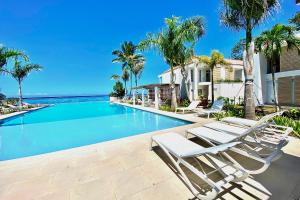 PaeaTropical paradise luxury的一座游泳池,位于一座带椅子和棕榈树的房子里