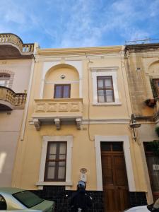 Għajn il-KbiraSir Patrick's rooms & hostel的黄色的建筑,有窗户和门
