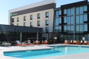 达拉斯Holiday Inn Dallas Market Ctr Love Field, an IHG Hotel的一座带桌椅的建筑前的游泳池