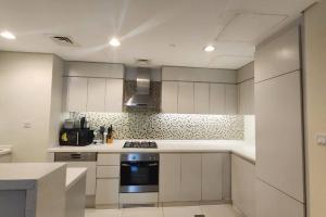 迪拜DAMAC Voleo In Business Bay的厨房配有白色橱柜和炉灶烤箱。