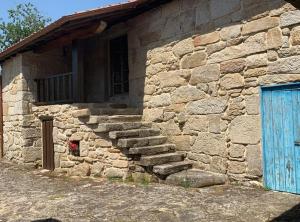 AmoeiroHabitaciones con baño individual en Casa de campo. Piscina.的一座石头建筑,设有蓝色的门和一些楼梯