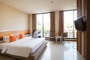 清迈Imm Hotel Thaphae Chiang Mai的坐在酒店房间床上的女人