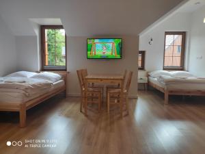 斯克拉斯卡波伦巴Szklarska Chata的客房设有两张床、一张桌子和一台电视机。