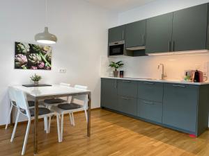 林茨Ebelsberger Terrassen的厨房配有绿色橱柜和桌椅