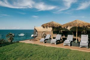 普莱诺斯Cavo Mare Mirazur Luxury Retreat with private pool的一组椅子和遮阳伞,靠近大海