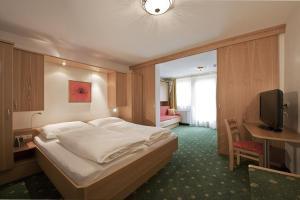 格罗萨尔格拉茨格罗萨尔酒店的一间卧室配有一张床、一张书桌和一台电视