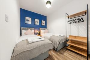 波特斯巴The Hertfordshire Hideaway的一间卧室设有两张床和蓝色的墙壁