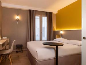 皇后堡ibis Styles Bourg La Reine的酒店客房配有一张床铺、一张桌子和一张书桌。