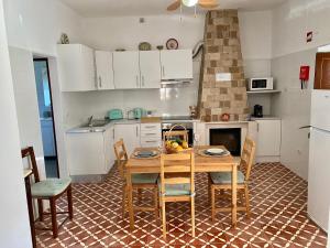 Casa Ti Barbara的一间带木桌和椅子的厨房和一间带白色橱柜的厨房