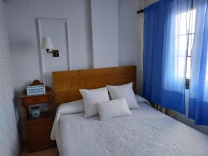 圣费尔南多Luz de la Bahía II - Bahía Sur - Cádiz的一间卧室配有白色的床、蓝色窗帘和窗户