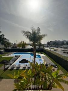 维拉摩拉Sublime Vilamoura Aquamar 106 by JG Apartments的一个带棕榈树和遮阳伞的游泳池