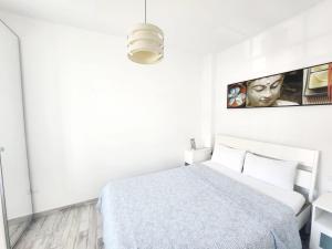 洛斯克里斯蒂亚诺斯Laika的白色的卧室配有一张床,墙上挂着一幅画