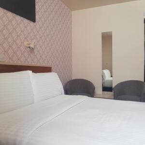 圣赫利尔泽西诺弗克酒店的卧室配有一张白色大床和两把椅子