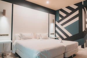马拉加Hotel Málaga Nostrum Airport的卧室配有一张白色大床和一堵墙