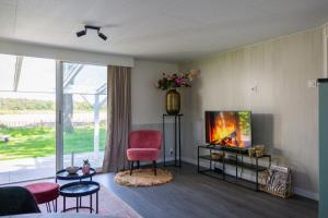 奥斯特韦克Bed & outdoor wellness - natuurhuisje Oisterwijk的客厅配有红色椅子和电视