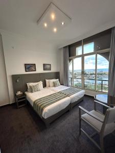 朱尼耶Bel Azur Hotel - Resort的一间卧室配有一张大床和一把椅子