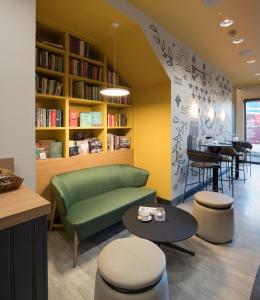 伦敦The Wesley Euston的一个带绿色沙发、桌子和椅子的图书馆