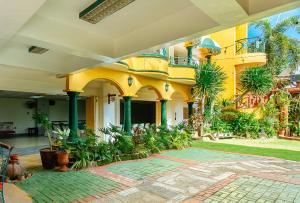 卡兰巴RedDoorz @ Yahweh Spring Retreat & Resort Laguna的一座棕榈树的黄色建筑和庭院