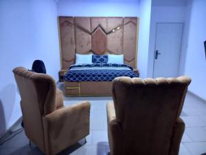 GwarinpaMega Pavilion Apartment And Suits Gwarinpa的一间卧室配有一张床和两把椅子