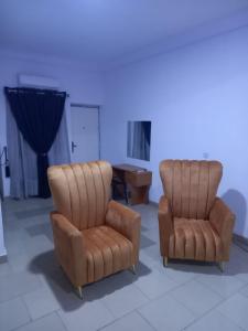 GwarinpaMega Pavilion Apartment And Suits Gwarinpa的两个皮椅和一张桌子