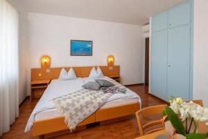 洛迦诺Hotel Rondinella Locarno的一间卧室配有一张大床和两张桌子