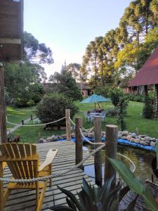 坎普阿莱格里Chalé Cafofo的一个带池塘和蓝伞的木制甲板
