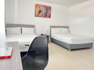 比亚维森西奥Hotel Vanguardia Natural的酒店客房配有两张床和一张桌子及椅子