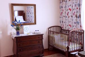 丰沙尔Casa Charmosa的一间卧室设有2张婴儿床、梳妆台和镜子