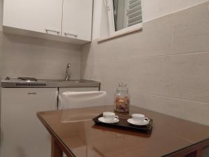 马卡尔斯卡Apartments Rose Loboja的厨房配有带2杯和1瓶的桌子