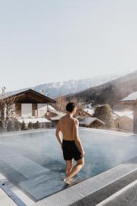 梅扎纳Hotel Ravelli Luxury Spa的站在游泳池的水面上的男人