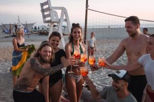 埃斯孔迪多港Secret Beach Hostel的一群比基尼人,在沙滩上戴着酒杯