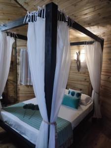 ApiaíCasa na Árvore - Chalé Quemeninho的卧室配有带白色窗帘的天蓬床