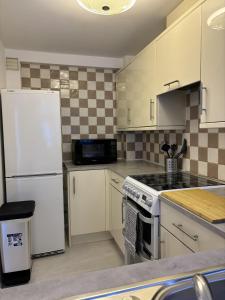 南安普敦Cosy Corner - 2 beds, free parking, garden, 2 mins walk to Southampton General Hospital的厨房配有白色橱柜和白色冰箱。