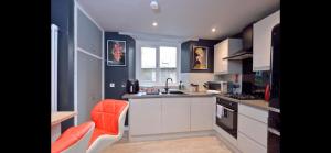 杰德堡Apartment in Scottish Borders的厨房配有白色橱柜和橙色椅子