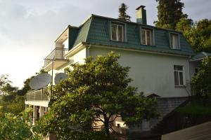 姆兹瓦内康茨基Green Cape Holiday Home的白色的房子,有绿色的屋顶和一棵树