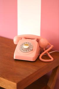 曼德琉-拉纳普勒Hotel Casarose - Cannes Mandelieu的木桌上方的粉红色电话