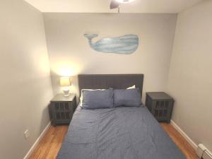 米尔福德Bobby's Beach Bungalow的一间卧室配有一张带2个床头柜的床,墙上挂有绘画作品