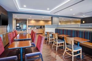 贝尔维尔TownePlace Suites by Marriott Detroit Belleville的一间带木桌椅的餐厅和一间酒吧