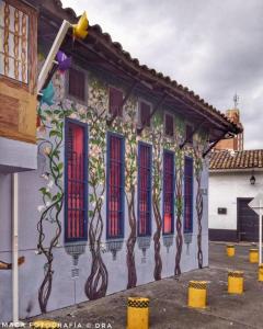 卡利HOSTAL CHONTADURO Casa colonial en pleno centro histórico de Cali- Se alquila la casa entera para 12 o 13 personas o por habitaciones的一座有树的建筑,在它的侧面上画着