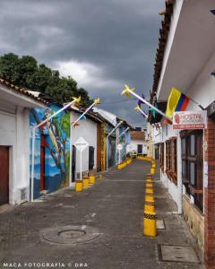 卡利HOSTAL CHONTADURO Casa colonial en pleno centro histórico de Cali- Se alquila la casa entera para 12 o 13 personas o por habitaciones的城市中一条有旗帜和建筑的空街道