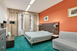 卡罗维发利Excellent apartments in Karlovy Vary的一间卧室拥有橙色的墙壁,配有一张床和一张沙发