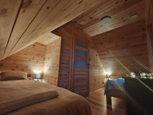 DomaszkówBAJKA-Domek na wsi的一间带木墙的卧室和一张位于客房内的床